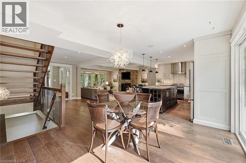 Open-concept main level featuring wood-finish flooring, a contemporary dining area with a glass-top table, and a tiered staircase with dark metal balusters - 266 Ferndale Place, Waterloo, ON - Indoor Photo Showing Other Room