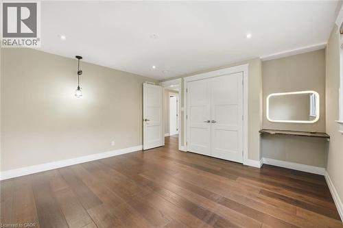 Spacious room featuring wood-finish flooring, recessed lighting, and a modern pendant light fixture - 266 Ferndale Place, Waterloo, ON - Indoor Photo Showing Other Room