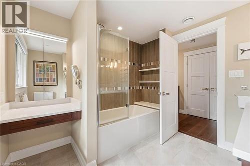 Full bathroom featuring a tub and shower combination with glass enclosure, integrated shelving, and vertical wood-finish wall tile accents - 266 Ferndale Place, Waterloo, ON - Indoor Photo Showing Bathroom
