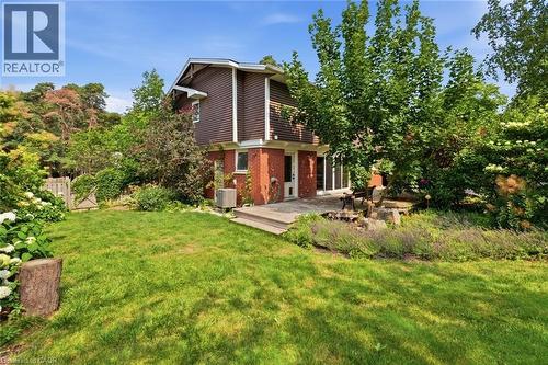 Expansive backyard featuring a manicured lawn, established landscaping, a multi-level wood deck, and mature perimeter trees - 266 Ferndale Place, Waterloo, ON - Outdoor