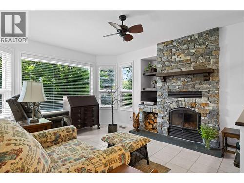 Family Room at front of home with striking rock fireplace and bright bay window - 3889 Gallaghers Grange, Kelowna, BC - Indoor Photo Showing Living Room With Fireplace