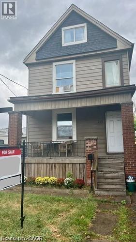 The property features a front porch with brick pillars and a white front door - 219 Avondale Street, Hamilton, ON - Outdoor With Deck Patio Veranda