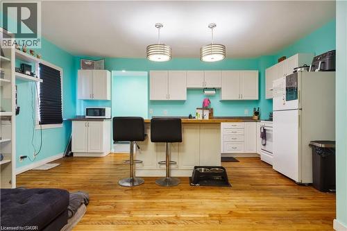 Open concept kitchen featuring light wood floors, white cabinetry, a kitchen island with seating, and a white refrigerator - 219 Avondale Street, Hamilton, ON - Indoor Photo Showing Kitchen
