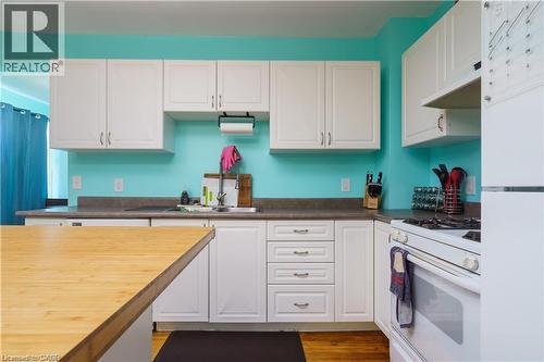 The kitchen features white cabinetry, a sink with a faucet, and a white oven range - 219 Avondale Street, Hamilton, ON - Indoor Photo Showing Kitchen With Double Sink