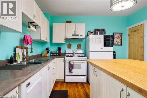 The kitchen features white cabinetry, a double basin sink, and a white refrigerator - 219 Avondale Street, Hamilton, ON - Indoor Photo Showing Kitchen With Double Sink
