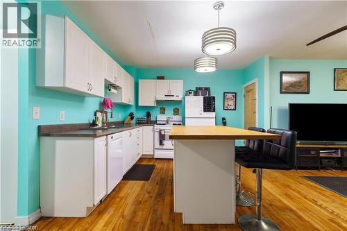 The kitchen features hardwood flooring, white cabinetry, and white appliances - 219 Avondale Street, Hamilton, ON - Indoor Photo Showing Kitchen