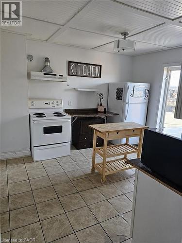 The kitchen features a white electric range, a white refrigerator, and tiled flooring - 219 Avondale Street, Hamilton, ON - Indoor Photo Showing Kitchen