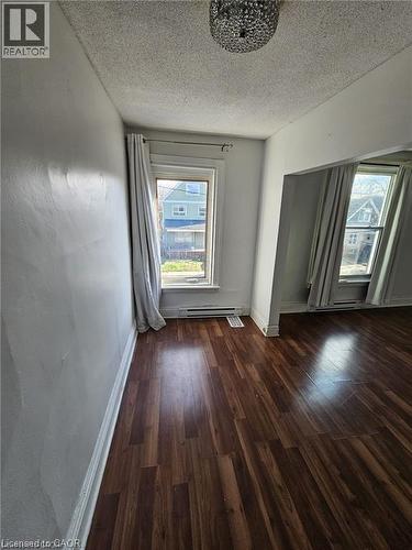 This room features dark-toned flooring, light-colored walls, and a decorative ceiling light fixture - 219 Avondale Street, Hamilton, ON - Indoor Photo Showing Other Room