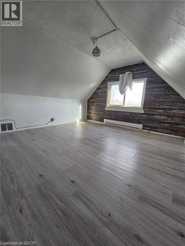 The property features an attic space with sloped ceilings, grey wood-look flooring, and a window providing natural light - 219 Avondale Street, Hamilton, ON - Indoor Photo Showing Other Room