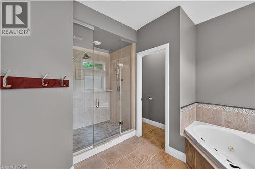 Bathroom featuring a glass-enclosed shower, a built-in corner soaking tub with tiled surround, and ceramic tile flooring - 2050 15 Side Road, Milton, ON - Indoor Photo Showing Bathroom