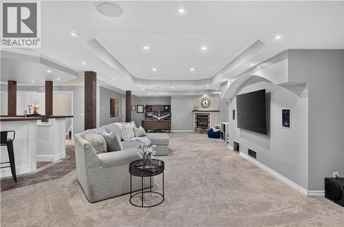 Spacious entertainment area featuring recessed lighting, a built-in fireplace with a stone surround, and carpet flooring - 2050 15 Side Road, Milton, ON - Indoor