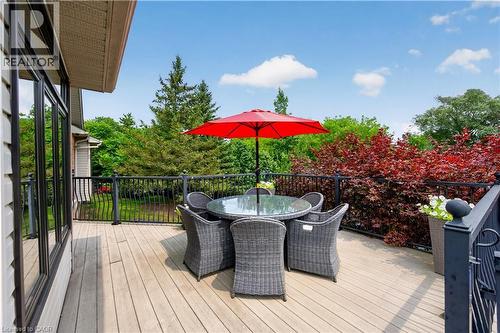 Expansive outdoor deck featuring wood-finish flooring, black metal railings, and vibrant surrounding foliage - 2050 15 Side Road, Milton, ON - Outdoor With Deck Patio Veranda With Exterior