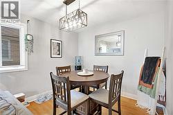 Dining area featuring wood-finish flooring and a rectangular metal chandelier - 