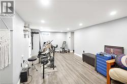 Spacious interior room featuring light gray walls, recessed lighting, and wood-finish flooring - 
