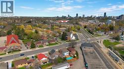 Aerial perspective showcasing a mixed-use urban landscape with residential homes, mature trees, commercial buildings, and a distant city skyline - 