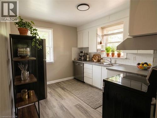 Kitchen featuring white cabinetry, grey countertops, wood-finish flooring, subway tile backsplash, and a stainless steel sink - 20 Lloyd Manor Road, Etobicoke, ON - Indoor Photo Showing Kitchen With Double Sink