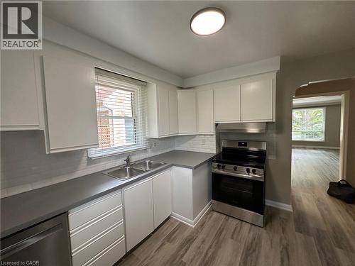 Modern kitchen featuring white cabinetry, grey countertops, stainless steel appliances, a subway tile backsplash, and wood-finish flooring - 20 Lloyd Manor Road, Etobicoke, ON - Indoor Photo Showing Kitchen With Double Sink