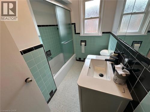 Bathroom featuring a modern vanity with integrated sink, black wall-mounted faucet, and a black-tiled backsplash - 20 Lloyd Manor Road, Etobicoke, ON - Indoor