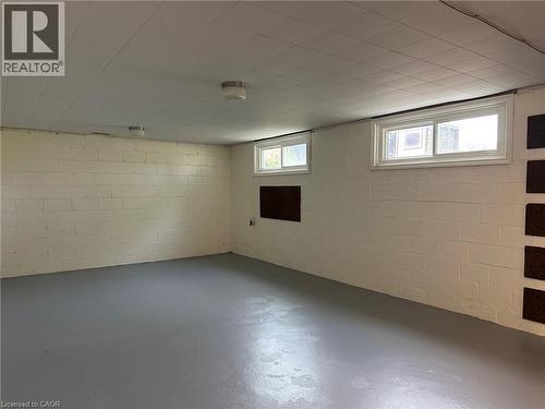 Spacious lower level room featuring painted concrete block walls, two windows with white trim, a grey painted concrete floor, and a white paneled ceiling with flush-mount lighting - 20 Lloyd Manor Road, Etobicoke, ON - Indoor