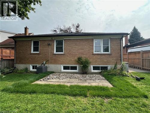 Rear exterior featuring brick siding, multiple windows, and a level lawn area with a concrete patio - 20 Lloyd Manor Road, Etobicoke, ON - Outdoor With Exterior