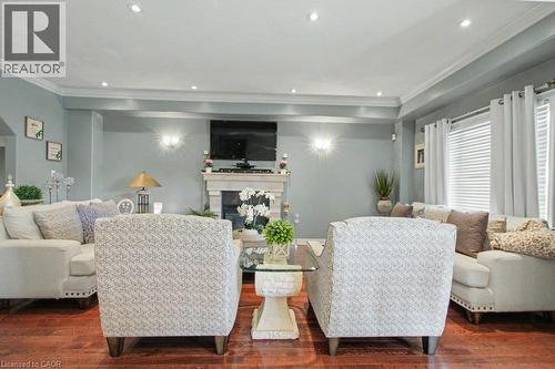 Living area featuring rich wood flooring, crown molding, recessed lighting, a stone fireplace, and sconce wall lighting - 284 Normanhurst Avenue, Hamilton, ON - Indoor Photo Showing Living Room With Fireplace