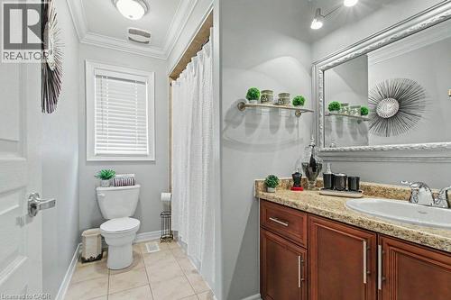 Bathroom featuring a single vanity with a laminate countertop, undermount sink, and wood-finish cabinetry - 284 Normanhurst Avenue, Hamilton, ON - Indoor Photo Showing Bathroom