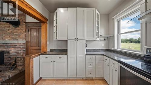 Kitchen featuring white shaker-style cabinetry, dark speckled countertops, and tile flooring - 3211 Highway 3, Jarvis, ON - Indoor Photo Showing Kitchen