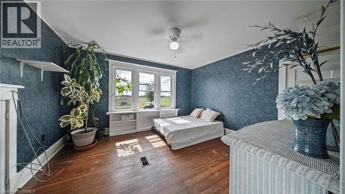 Inviting room with dark blue textured wallpaper and warm-toned wood-finish flooring - 3211 Highway 3, Jarvis, ON - Indoor