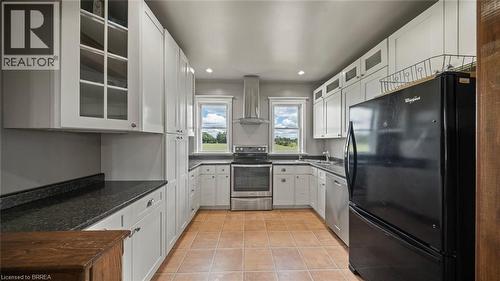 U-shaped kitchen featuring white cabinetry, dark countertops, stainless steel appliances, and terra cotta tile flooring - 3211 Highway 3, Jarvis, ON - Indoor Photo Showing Kitchen
