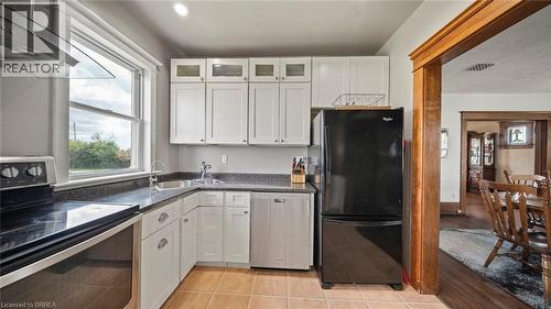 Kitchen featuring white cabinetry, dark speckled countertops, and an integrated stainless steel dishwasher - 3211 Highway 3, Jarvis, ON - Indoor Photo Showing Kitchen