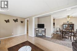 Open-concept living space featuring light wood-finish flooring, neutral wall tones, a broad entryway, and a ceiling fan in the dining area - 