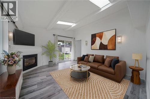 Living area featuring wood-finish flooring, a fireplace with a white mantel, and ceiling skylights - 7332 Twenty Road E, Glanbrook, ON - Indoor Photo Showing Living Room With Fireplace