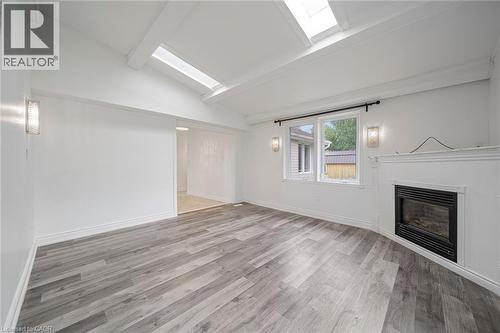 Vaulted ceilings with exposed beams and skylights complement the wood-finish flooring - 7332 Twenty Road E, Glanbrook, ON - Indoor With Fireplace
