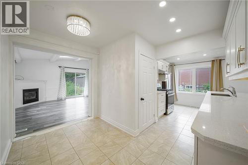 Kitchen featuring tiled flooring, white cabinetry with gold-tone hardware, a stainless steel sink, and light-toned countertops - 7332 Twenty Road E, Glanbrook, ON - Indoor Photo Showing Other Room