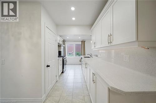 Galley kitchen featuring white cabinetry, light-toned countertops, tile flooring, and recessed lighting - 7332 Twenty Road E, Glanbrook, ON - Indoor Photo Showing Kitchen