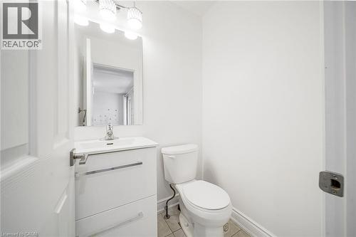 Bathroom featuring a white vanity with integrated sink, rectangular mirror, and modern three-light fixture - 7332 Twenty Road E, Glanbrook, ON - Indoor Photo Showing Bathroom