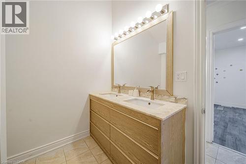 Dual vanity featuring a light wood-finish cabinet with six drawers, an integrated stone countertop, and two undermount sinks - 7332 Twenty Road E, Glanbrook, ON - Indoor Photo Showing Bathroom