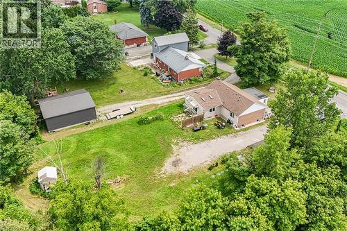 Expansive property featuring a main residence with a light-colored exterior and brown roof, a detached dark-paneled outbuilding with a metal roof, and a gravel driveway - 7332 Twenty Road E, Glanbrook, ON - Outdoor
