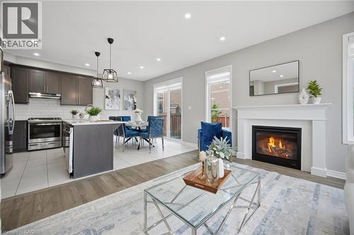 Open-concept living space featuring a white mantel fireplace, wood-finish flooring, and recessed lighting - 542 Boyd Lane, Milton, ON - Indoor Photo Showing Living Room With Fireplace