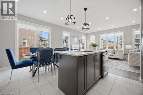 Modern kitchen island with a white countertop and a stainless steel sink, complemented by two black geometric pendant lights - 542 Boyd Lane, Milton, ON - Indoor