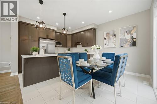 Contemporary kitchen and dining area featuring dark wood-finish cabinetry, stainless steel appliances, a white subway tile backsplash, and light-colored tile flooring - 542 Boyd Lane, Milton, ON - Indoor Photo Showing Dining Room