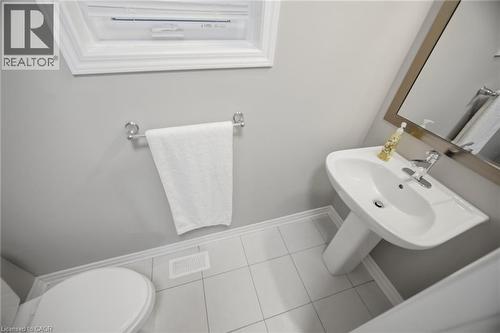 Compact bathroom featuring a white pedestal sink, chrome faucet, and a wall-mounted mirror with a brushed metal frame - 542 Boyd Lane, Milton, ON - Indoor Photo Showing Bathroom