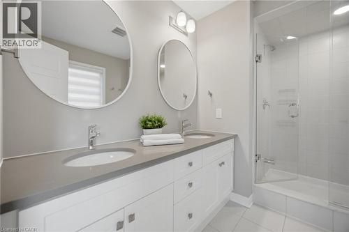 Double vanity with white cabinetry and integrated sinks, complemented by a glass-enclosed shower with subway tile surround, polished chrome fixtures, and neutral floor tiling - 542 Boyd Lane, Milton, ON - Indoor Photo Showing Bathroom