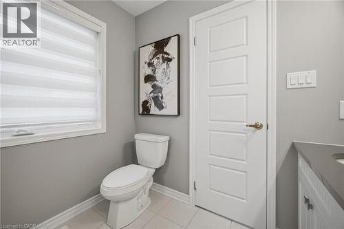 Bathroom featuring a single window with blinds, a sleek white toilet, light gray walls, a four-panel interior door, and a built-in vanity with a gray countertop - 542 Boyd Lane, Milton, ON - Indoor Photo Showing Bathroom