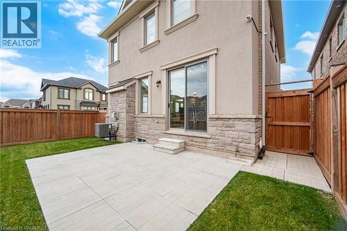 Private fenced backyard featuring a spacious patio, a well-maintained lawn, and a sliding glass door entry to the interior - 542 Boyd Lane, Milton, ON - Outdoor