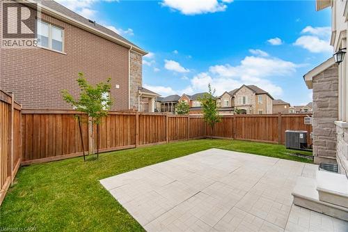 Expansive backyard featuring a stone patio, manicured lawn, and privacy fencing - 542 Boyd Lane, Milton, ON - Outdoor