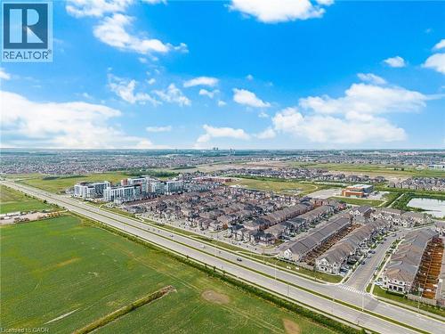 Aerial perspective showcasing a developed residential area with varied housing types, expansive green fields, and a multi-lane roadway - 542 Boyd Lane, Milton, ON - Outdoor With View