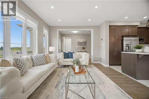Open-concept living space featuring wood-finish flooring, a kitchen island with white countertop, dark wood-finish cabinetry, stainless steel refrigerator, and recessed lighting - 542 Boyd Lane, Milton, ON - Indoor Photo Showing Living Room