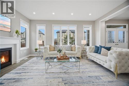 Spacious living area featuring light wood-finish flooring, a white mantel fireplace, and recessed lighting - 542 Boyd Lane, Milton, ON - Indoor Photo Showing Living Room With Fireplace