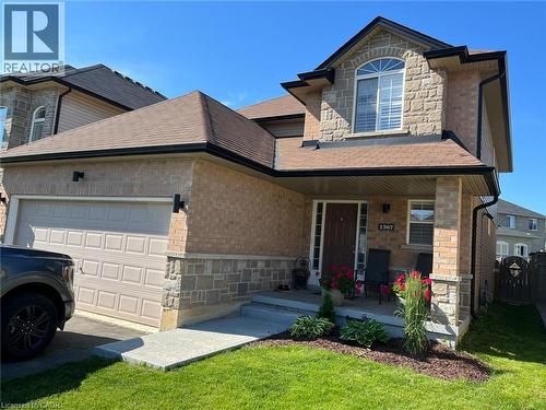 Brick and stone facade residence featuring an arched window, covered porch, attached garage, and manicured landscaping - 1367 Upper Paradise Road, Hamilton, ON - Outdoor